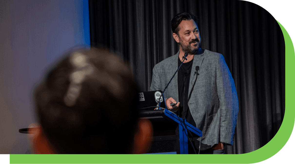Assignar CEO Sean McCreanor speaking on stage about AI in construction at a Build Better customer event.