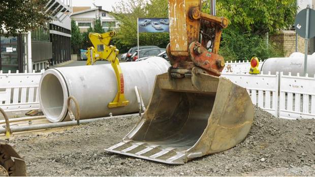 Excavator working alongside precast pipe